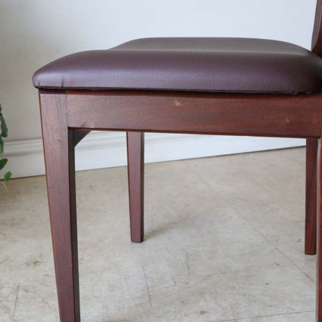 Vintage British mid-century teak dining chair leg and dark brown leather seat cushion with sleek wood grain detailing.