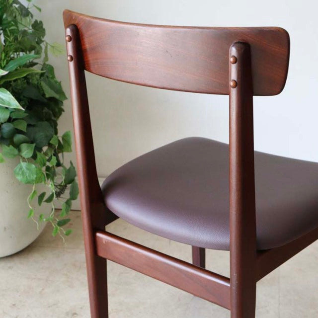 Vintage mid-century British dining chair in teak with curved backrest and smooth brown leather seat.