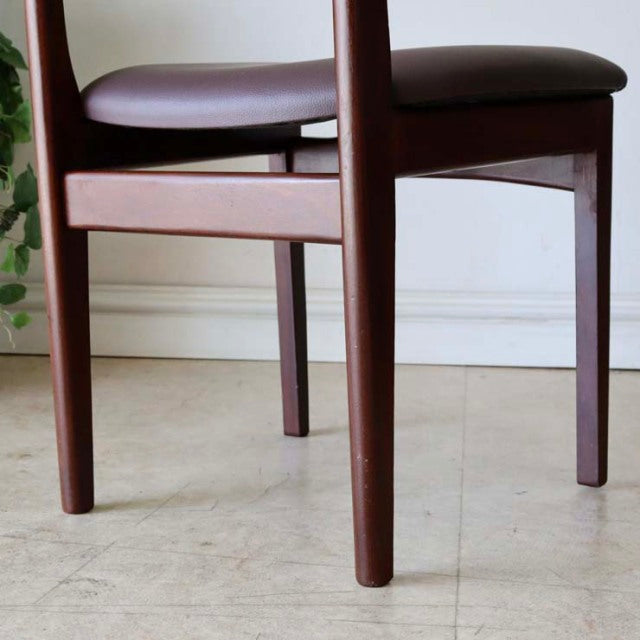 Vintage British mid-century teak dining chair with smooth wood grain, tapered legs, and dark cushioned seat.