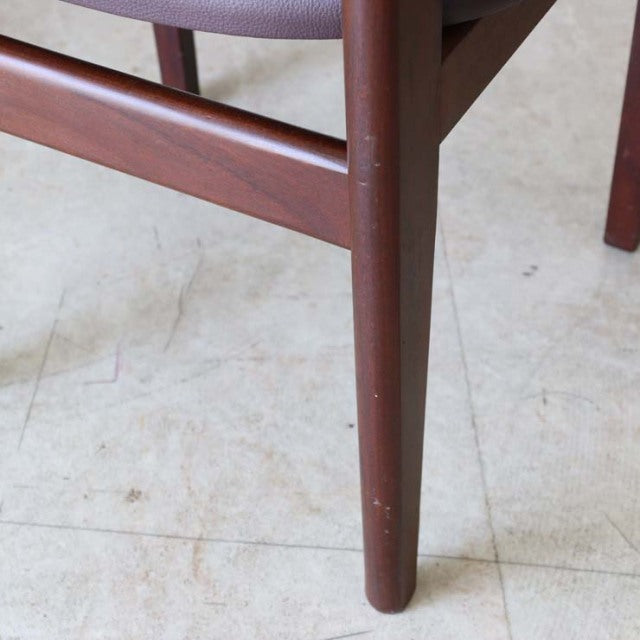 Mid-century British vintage teak dining chair leg with smooth wood grain and tapered design on light floor.