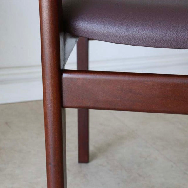 Close-up of vintage teak dining chair leg and stretcher with smooth grain and mid-century British design features.