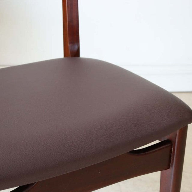 Mid-century British vintage teak dining chair with smooth dark brown leather seat and slender wooden frame.