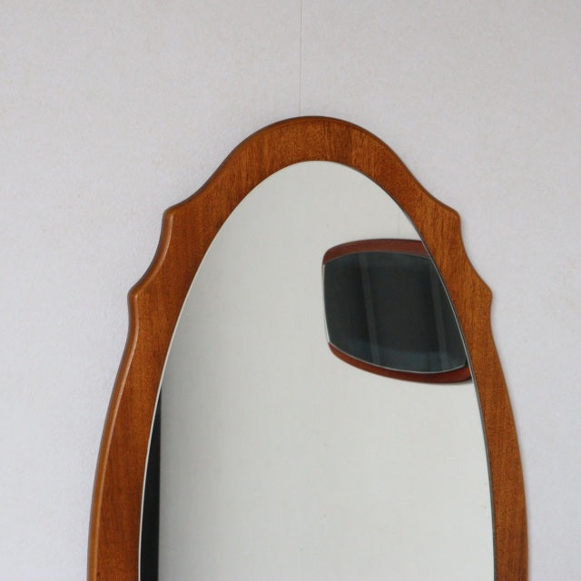 Oval vintage British mid-century teak wall mirror with smooth rounded edges and visible wood grain.
