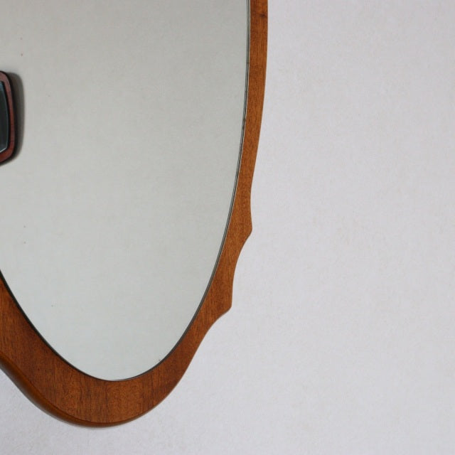 Oval mid-century British vintage wall mirror with teak frame featuring smooth wood grain and subtle carved details.
