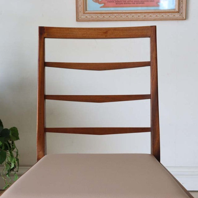 Mid-century British vintage teak dining chair with ladder back and beige seat cushion.