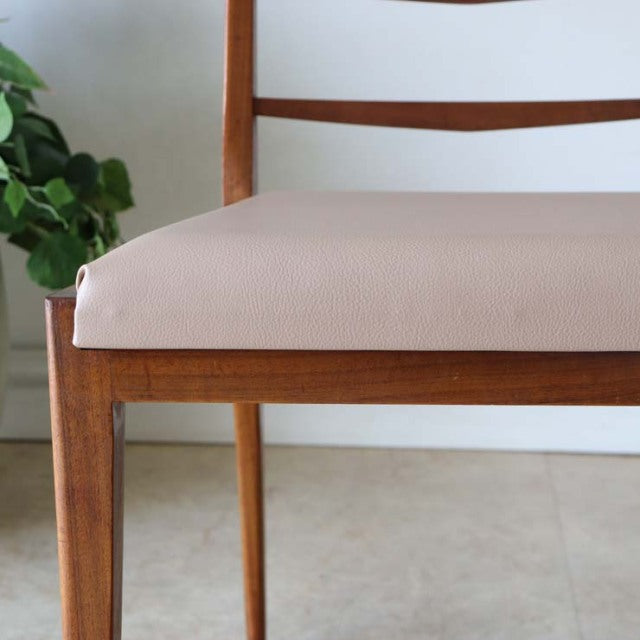 Set of four vintage mid-century British teak ladder dining chairs with beige upholstered seats and slender tapered legs.
