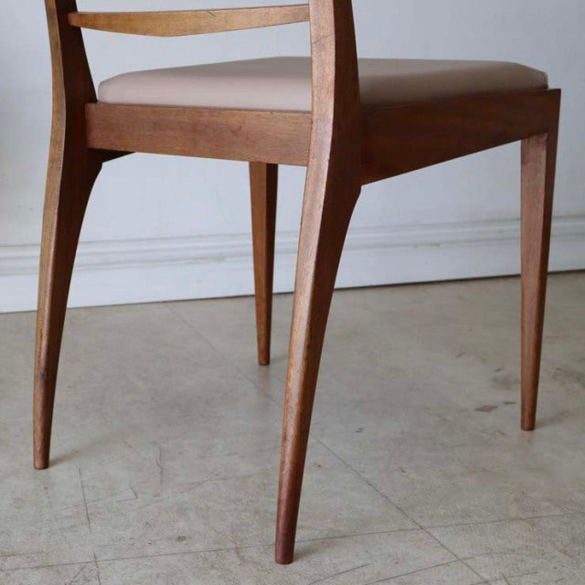 Mid-century British teak dining chair with slender tapered legs and smooth wood grain finish.