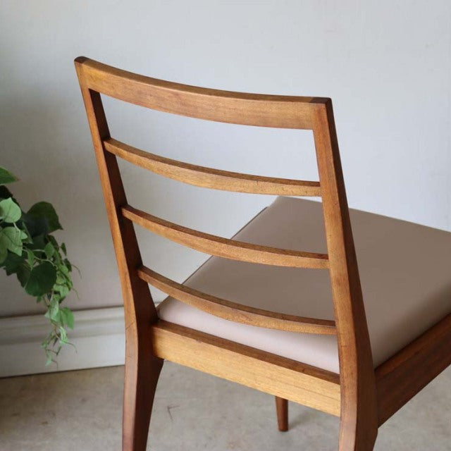 Set of four vintage McIntosh teak dining chairs with mid-century British design, horizontal slat backs, and beige.