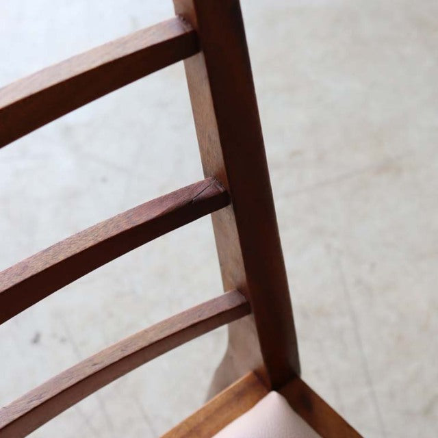 Close-up of vintage teak McIntosh ladder dining chair legs and rungs showing warm wood grain and mid-century British design.