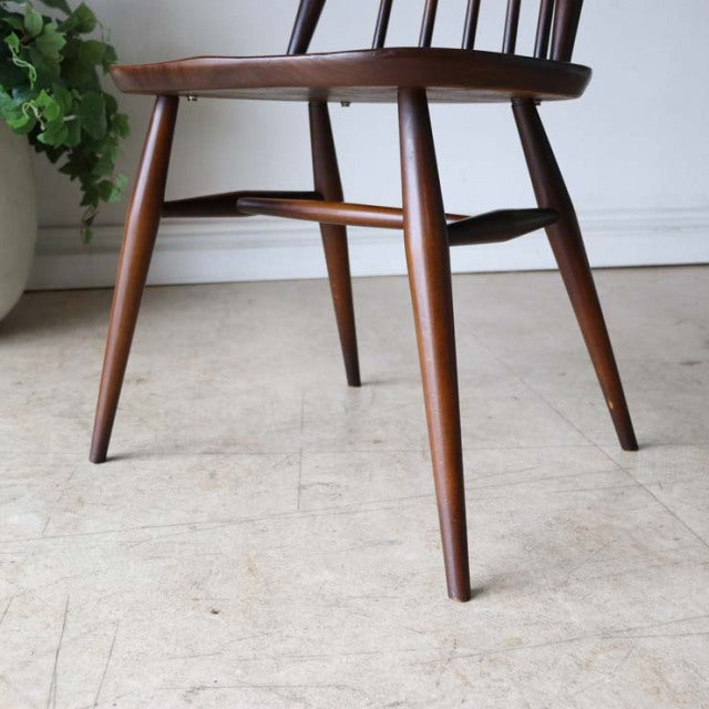 Mid-century British vintage teak dining chair leg detail with smooth wood grain and tapered rounded legs.