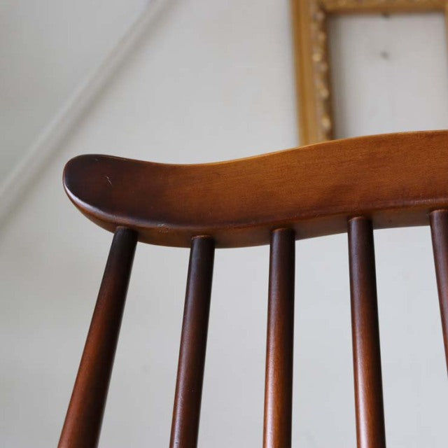 Close-up of mid-century British Ercol Goldsmith dining chair showcasing smooth teak wood grain and slender vertical spindles.