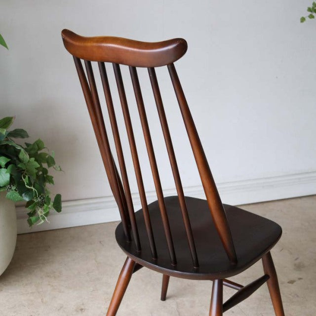 Pair of British mid-century ERCOL Goldsmith highback dining chairs in vintage teak with curved spindle backs and dark.