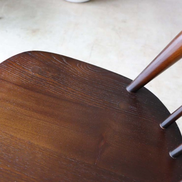 Close-up of vintage British mid-century teak dining chair seat showing rich wood grain and slender, rounded spindled.