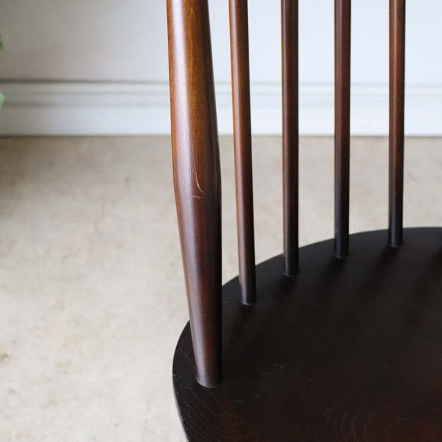Close-up of vintage British mid-century teak dining chair leg and spindle back with rich wood grain and smooth finish.