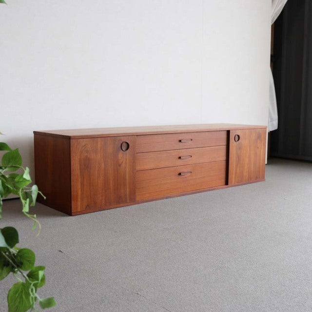 Mid-century British teak sideboard by Avalon with smooth wood grain, recessed circular handles, and clean, rectangular form.