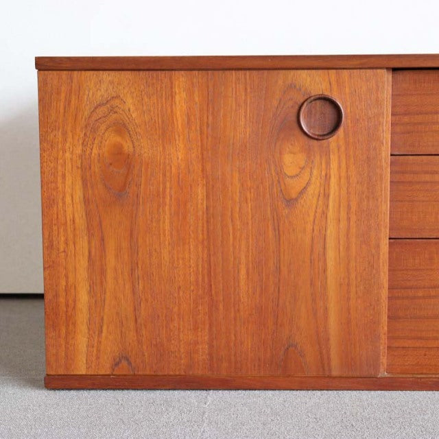 Vintage teak sideboard door panel with round recessed handle, showcasing rich wood grain and smooth mid-century British.