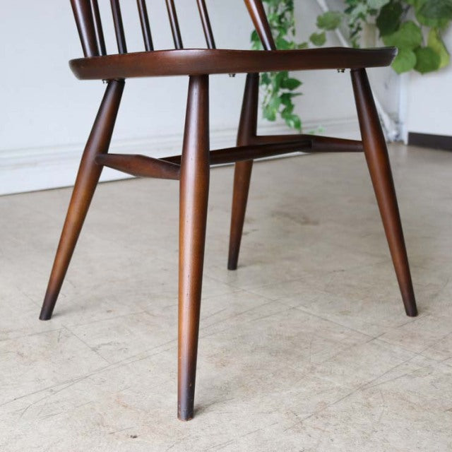Mid-century British vintage Ercol Goldsmith dining chair in teak with spindle back and tapered legs showing natural wood.