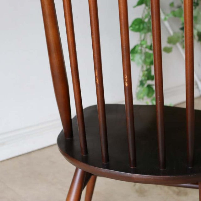 Mid-century British Ercol Goldsmith dining chair in vintage teak with slender spindle back and smooth round seat.