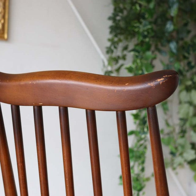 Brown teak vintage British mid-century dining chair backrest with smooth curved top rail and vertical spindles.