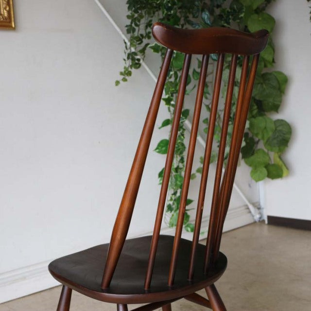 Vintage British mid-century teak dining chair with slender spindled backrest and dark leather seat cushion.