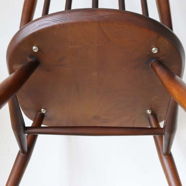Vintage British Ercol Goldsmith dining chair in teak with smooth curved seat, tapered legs, and visible wood grain.