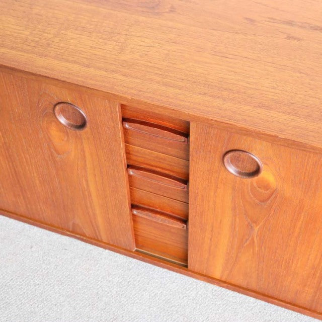 Mid-century vintage teak sideboard by Avalon with smooth wood grain, rounded recessed handles, and central vertical drawer.