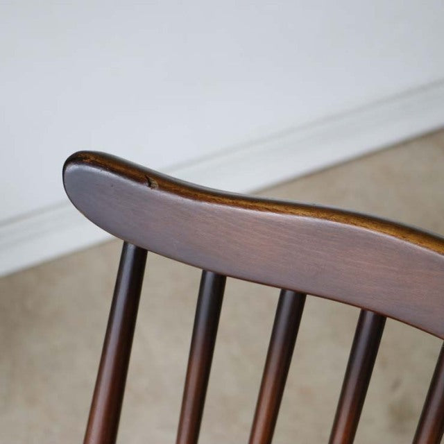 Close-up of vintage British mid-century Ercol Goldsmith chair backrest in dark teak with curved top rail and slender.