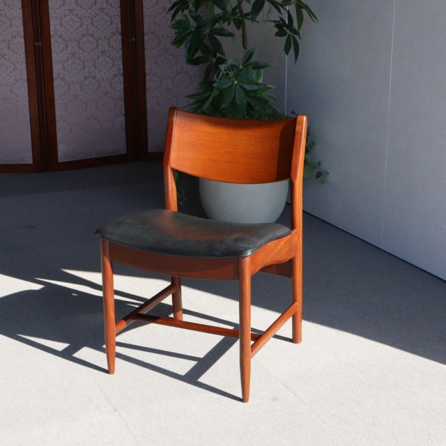 Vintage British mid-century teak dining chair with black leather seat and clean wood grain finish.