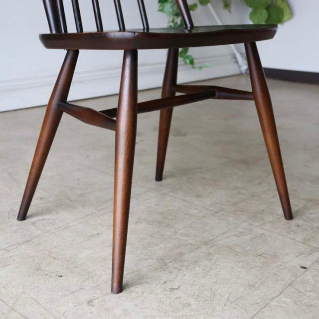 Mid-century British vintage teak dining chair with tapered legs and spindle back, smooth wood grain finish.