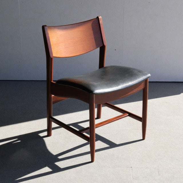 Mid-century British vintage dining chair with teak wood frame and black leather seat, smooth curved backrest and tapered.
