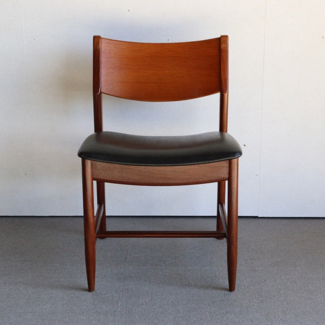 Vintage mid-century British teak dining chair with black leather seat and curved backrest, slender tapered legs and visible.