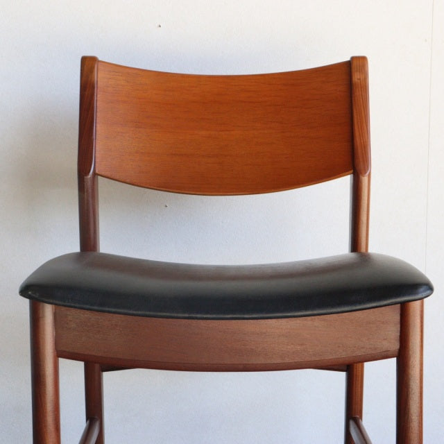 Vintage British mid-century teak dining chair with curved backrest and black leather seat cushion.