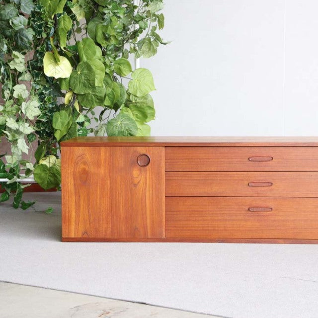 Mid-century British teak sideboard by AVALON with rich wood grain, round handle, and sleek tapered legs.