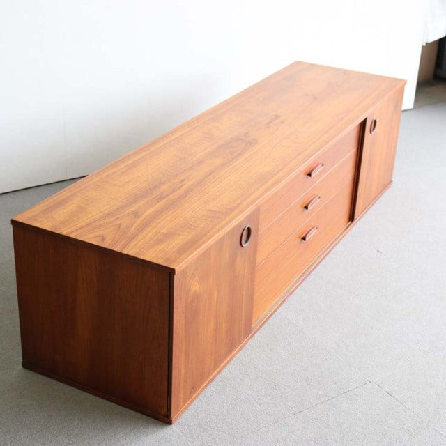 Mid-century teak sideboard by Avalon with smooth wood grain, round recessed handles, and tapered legs in British-Denmark.
