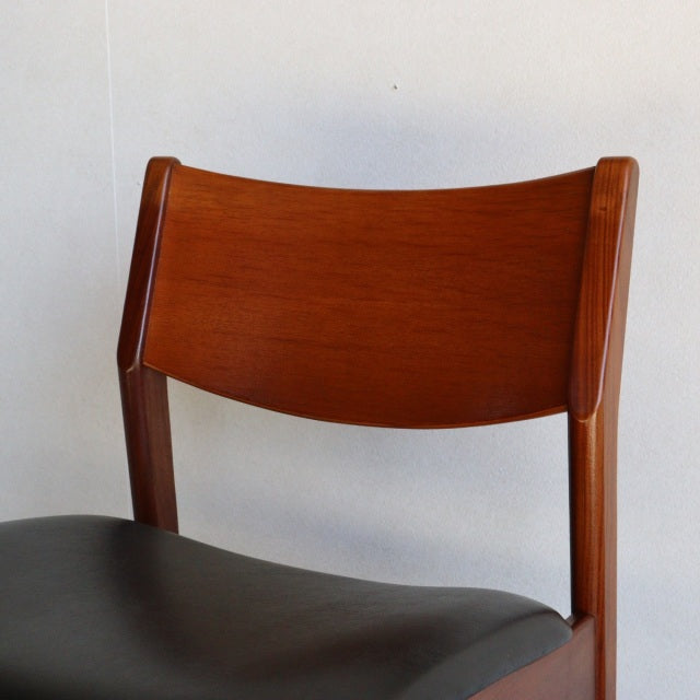 British vintage mid-century dining chair with curved teak wood backrest and black leather seat.