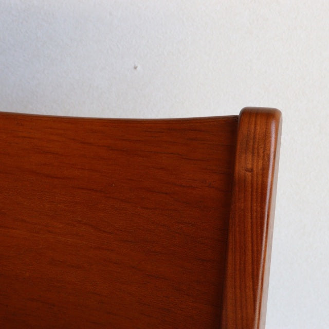 Close-up of vintage teak chair backrest showing rich wood grain with smooth, rounded edges in British mid-century design.