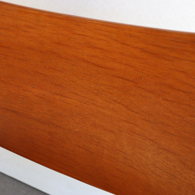 Mid-century British vintage teak chair backrest with smooth wood grain and warm amber tone.