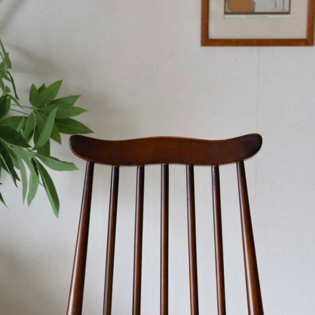 Vintage mid-century British Ercol dining chair in warm teak with curved top rail and slender vertical spindles.