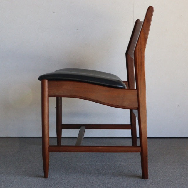 Mid-century British vintage dining chair with rich teak wood frame and black leather seat cushion, showcasing sleek tapered.