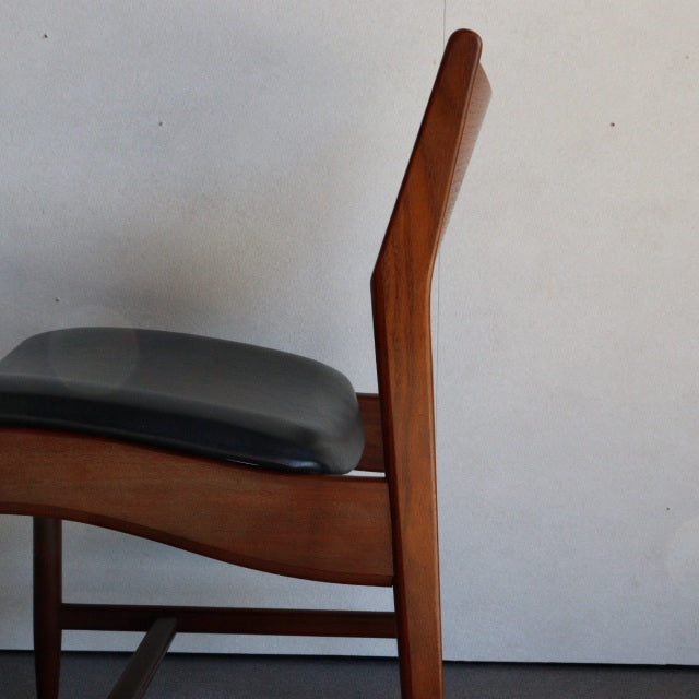 Mid-century British vintage dining chair with teak wood frame and black leather seat, showcasing sleek straight legs and.