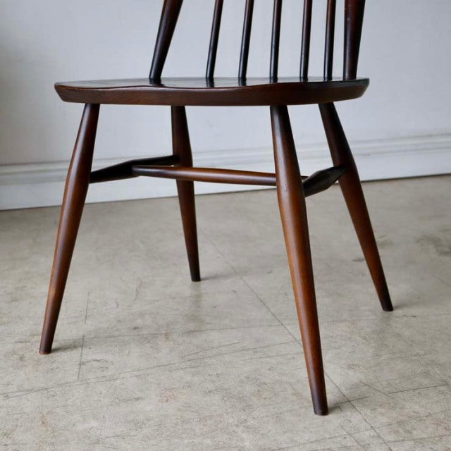 Mid-century British vintage teak dining chair by Ercol with tapered legs and curved spindled backrest.