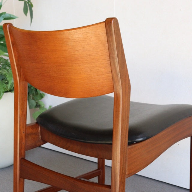 Mid-century British vintage dining chair with polished teak frame and black leather seat, smooth curved backrest and tapered .