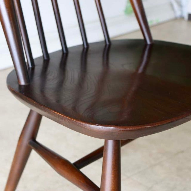 Mid-century British vintage Ercol dining chair in rich teak with smooth curved seat and slender spindle backrest.