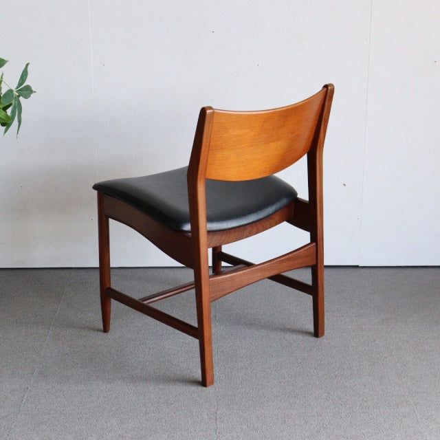 Vintage mid-century British dining chair with teak wood frame, black leather seat, and clean lines.