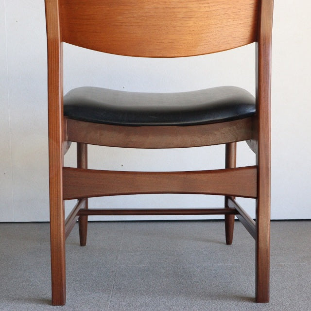 Mid-century British vintage dining chair with teak wood frame, black leather seat, straight legs, and visible wood grain.