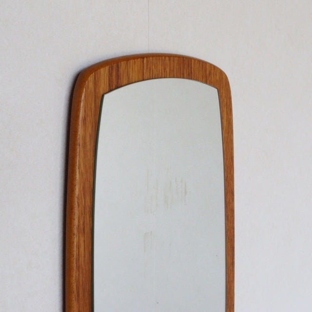 Vintage mid-century British teak wall mirror with elongated oval shape and smooth wood grain frame.