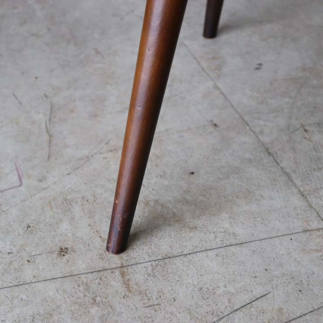 Teak tapered leg with visible grain from British mid-century vintage Ercol Goldsmith dining chair on concrete floor.
