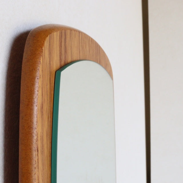 Vintage mid-century British teak wall mirror with elongated oval shape and warm wood grain finish.