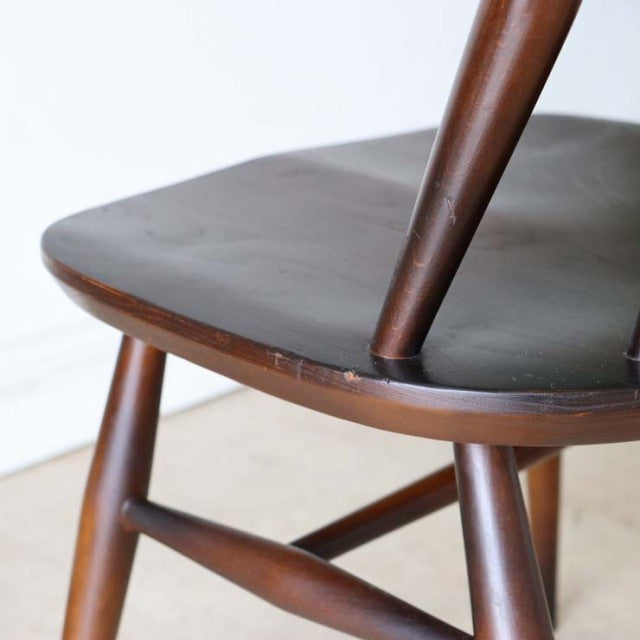 Close-up of vintage British mid-century Ercol Goldsmith dining chair seat in smooth teak with visible wood grain and tapered .