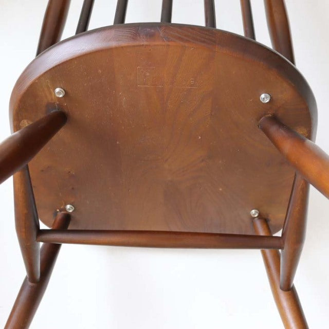 Underside view of vintage British Ercol Goldsmith teak high-back chair showing smooth wood grain, rounded legs, and sturdy.